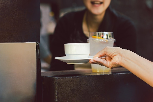 Mujer barista sirviendo una taza de café en la cafetería