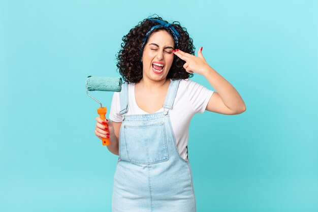 Mujer bastante árabe que parece infeliz y estresada, gesto de suicidio haciendo signo de pistola. concepto de casa de pintura