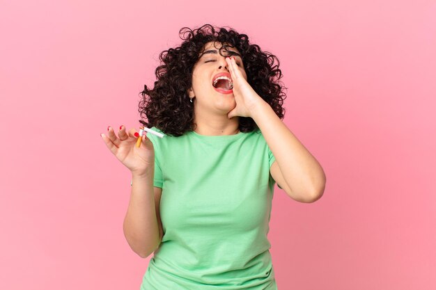 Mujer bastante árabe que se siente feliz, dando un gran grito con las manos al lado de la boca. concepto de no fumar