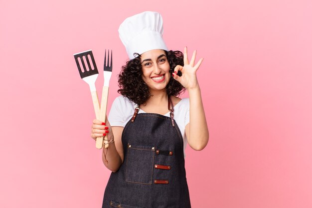 Mujer bastante árabe que se siente feliz, mostrando aprobación con gesto bien. concepto de chef de barbacoa