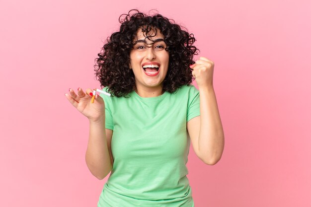 Mujer bastante árabe que se siente sorprendida, riendo y celebrando el éxito. concepto de no fumar