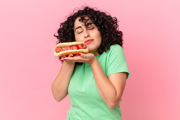 Mujer bastante árabe sosteniendo un perrito caliente. concepto de comida rapida