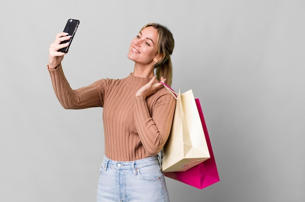 Foto mujer bastante caucásica con bolsas de compras y un teléfono inteligente