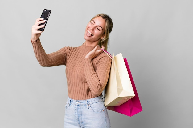 Foto mujer bastante caucásica con bolsas de compras y un teléfono inteligente