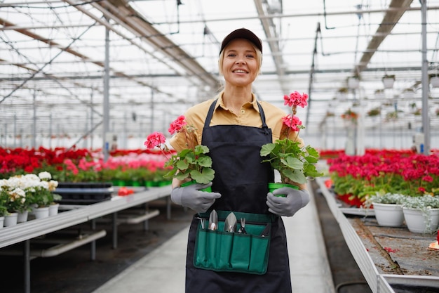 Mujer bastante caucásica con flores en las manos en el invernadero