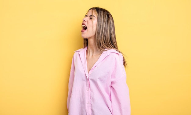 Mujer bastante caucásica gritando furiosamente, gritando agresivamente, luciendo estresada y enojada