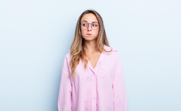 Mujer bastante caucásica preguntándose, pensando en pensamientos e ideas felices, soñando despierto, buscando copiar espacio en el costado