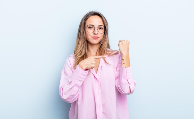 Mujer bastante caucásica que parece impaciente y enojada señalando el reloj pidiendo puntualidad quiere llegar a tiempo