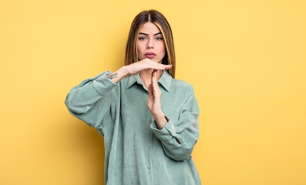 Una mujer bastante caucásica que parece seria, enojada y disgustada, haciendo señal de tiempo de espera