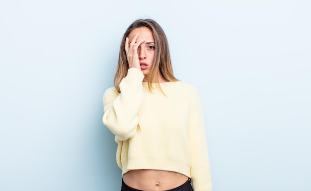 Mujer bastante caucásica que se siente aburrida, frustrada y con sueño después de una tarea aburrida, aburrida y tediosa, sosteniendo la cara con la mano