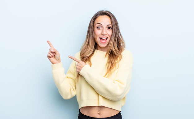 Mujer bastante caucásica que se siente alegre y sorprendida sonriendo con una expresión de asombro y apuntando hacia un lado