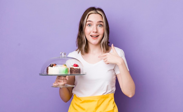 Una mujer bastante caucásica que se siente feliz y se señala a sí misma con un emocionado concepto de pasteles caseros