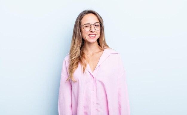 Mujer bastante caucásica que se ve feliz y amigable, sonriendo y guiñándote un ojo con una actitud positiva