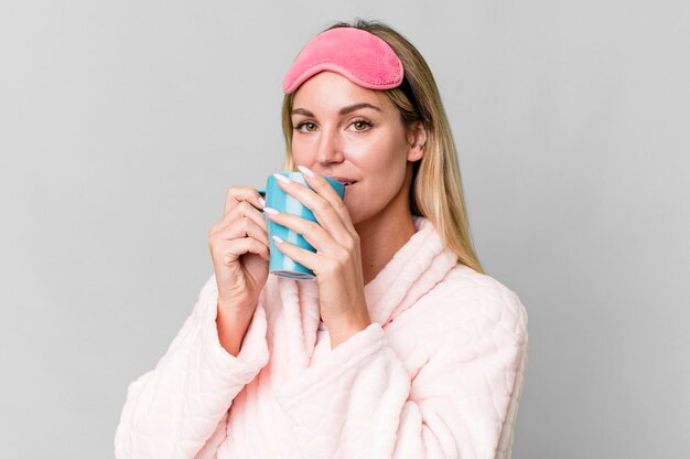 Mujer bastante caucásica con ropa de noche y tomando una taza de café para el desayuno