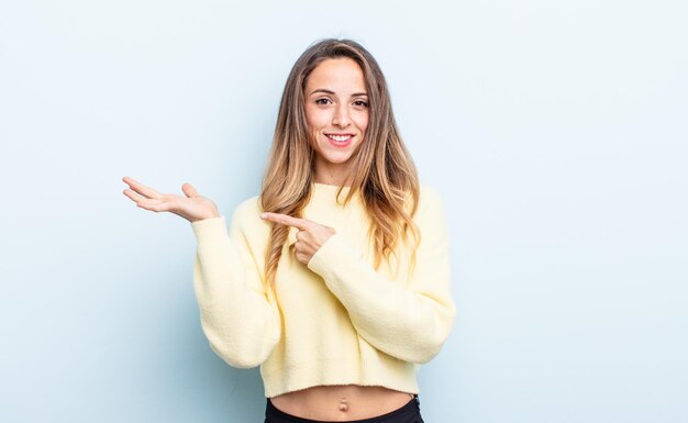 Mujer bastante caucásica sonriendo alegremente y apuntando a copiar espacio en la palma de la mano, mostrando o publicitando un objeto