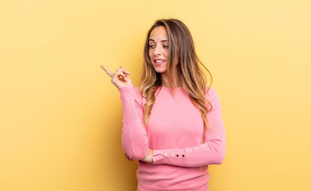 Mujer bastante caucásica sonriendo alegremente y mirando hacia los lados preguntándose si pensar o tener una idea