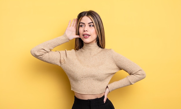 Mujer bastante caucásica sonriendo, mirando curiosamente a un lado, tratando de escuchar chismes o escuchando un secreto