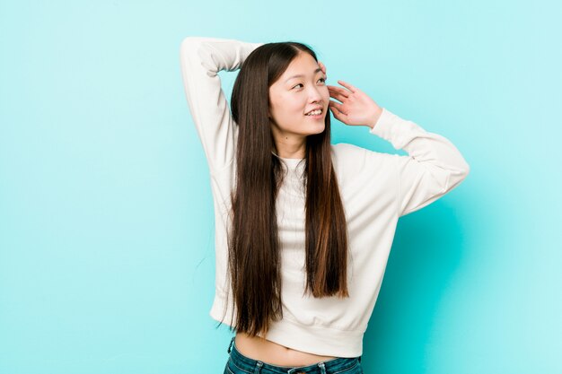 Mujer bastante china joven que estira los brazos, posición relajada.