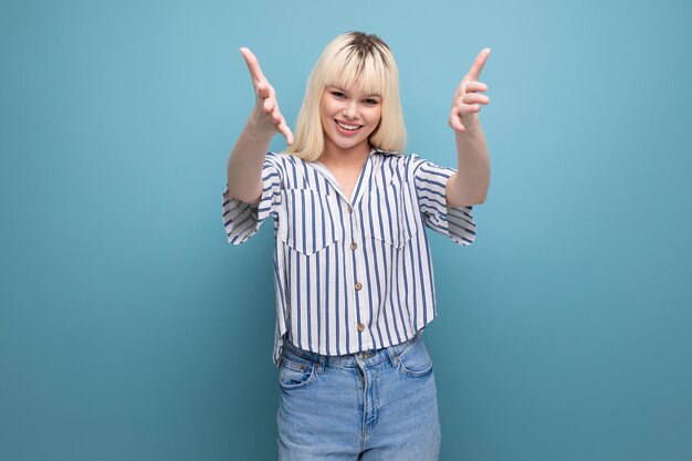 Mujer bastante europea enérgica positiva con camisa a rayas en el fondo del estudio