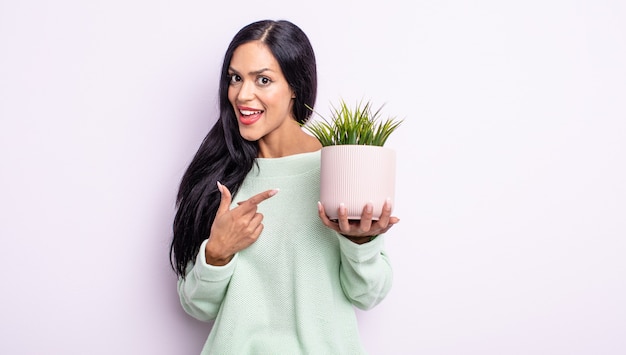 Mujer bastante hispana que parece emocionada y sorprendida apuntando hacia el lado. concepto de planta de casa