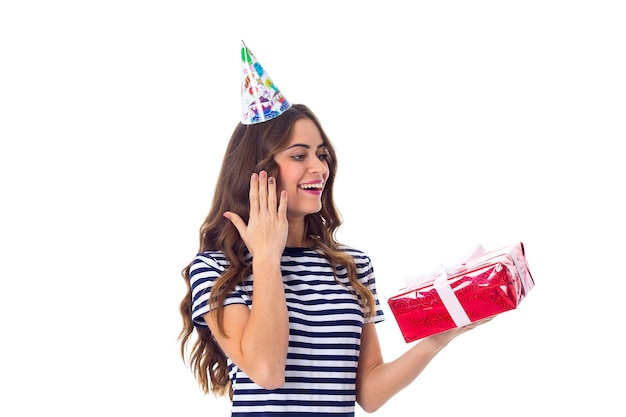 Una mujer bastante joven con camiseta despojada y gorra de celebración con regalos rojos y globos de colores