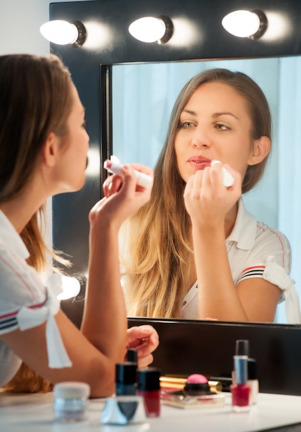 Mujer bastante joven que aplica el lápiz labial