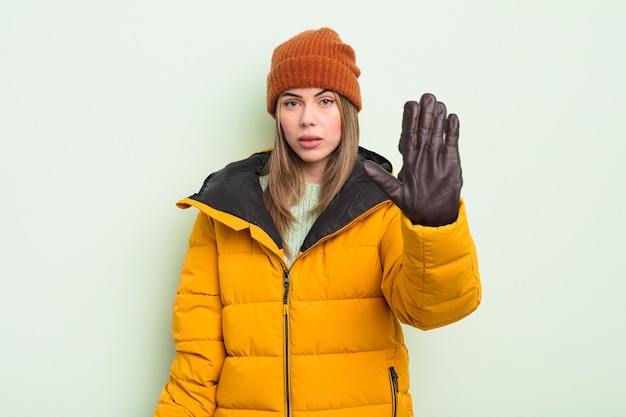 Mujer bastante joven que parece seria mostrando la palma abierta haciendo un gesto de parada concepto de clima frío