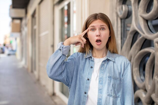 Mujer bastante joven que parece sorprendida con la boca abierta sorprendida al darse cuenta de una nueva idea o concepto de pensamiento