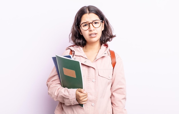 Mujer bastante joven que se siente desconcertada y confundida. estudiante con concepto de libros