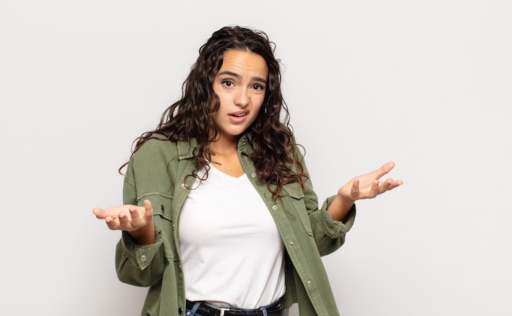 Foto mujer bastante joven que se siente despistada y confundida, no está segura de qué opción elegir, preguntándose