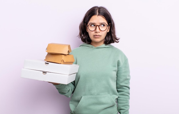 Mujer bastante joven que se siente triste, molesta o enojada y mira hacia un lado. concepto de comida rápida para llevar