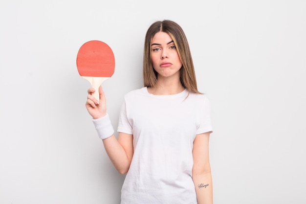 Mujer bastante joven que se siente triste y quejumbrosa con una mirada infeliz y un concepto de ping pong llorando