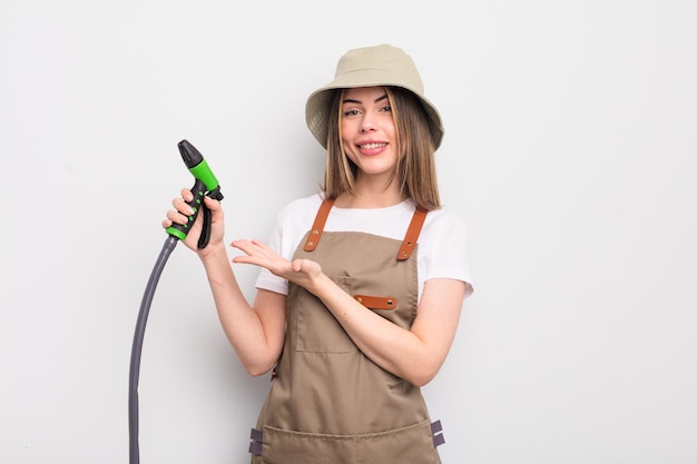 Mujer bastante joven sonriendo alegremente sintiéndose feliz y mostrando un concepto de riego de jardinero