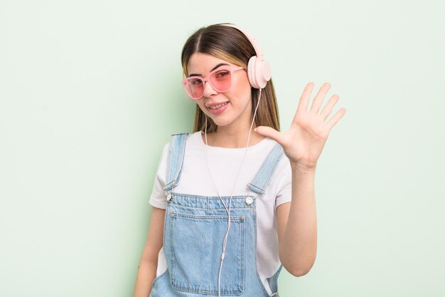 Una mujer bastante joven sonriendo y luciendo amigable mostrando el concepto de escuchar música número cinco