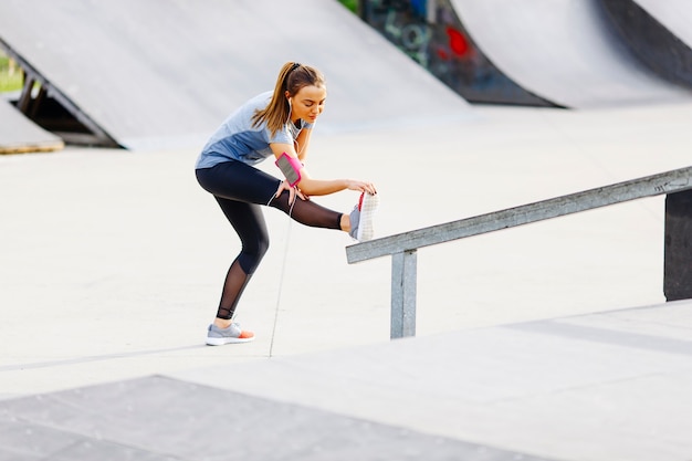 La mujer bastante joven tiene entrenamiento al aire libre en un día soleado