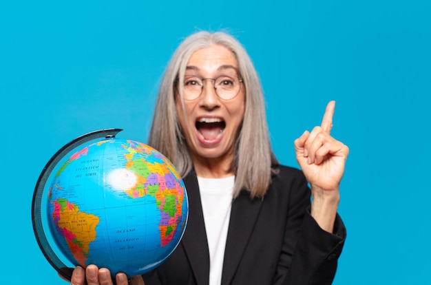 Mujer bastante mayor con un globo terráqueo. concepto de mundo