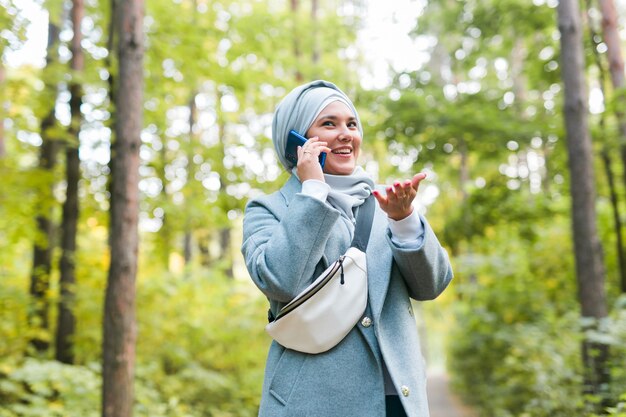 Mujer bastante musulmana hablar por teléfono en el parque.