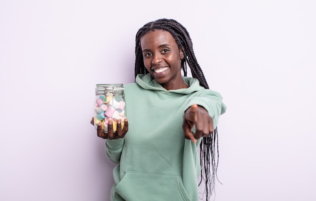 Mujer bastante negra apuntando a la cámara eligiéndote. concepto de caramelos de gelatina