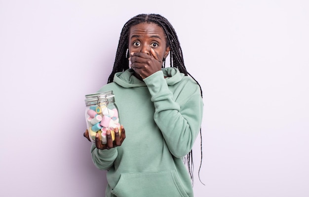 Mujer bastante negra que cubre la boca con las manos con una sorpresa. concepto de caramelos de gelatina