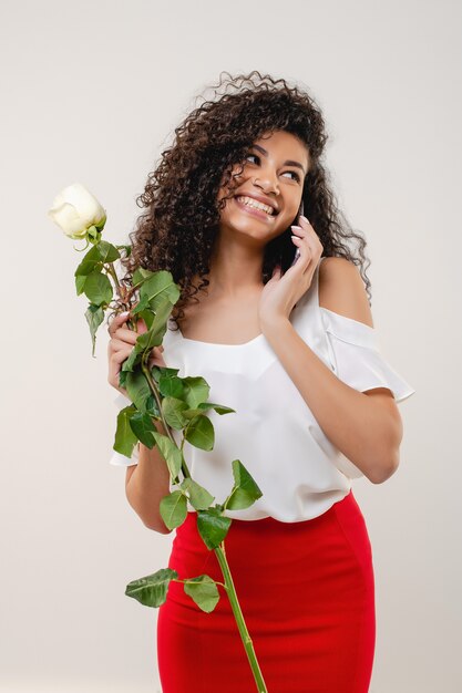 Mujer bastante negra con rose hablando por teléfono aislado