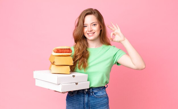 Mujer bastante pelirroja sosteniendo cajas de comida rápida para llevar