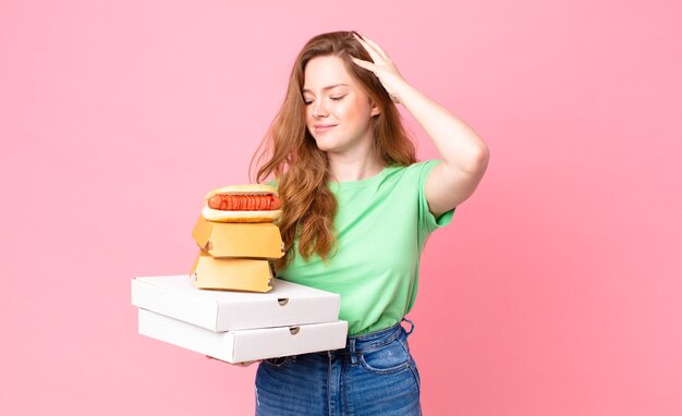 Mujer bastante pelirroja sosteniendo cajas de comida rápida para llevar