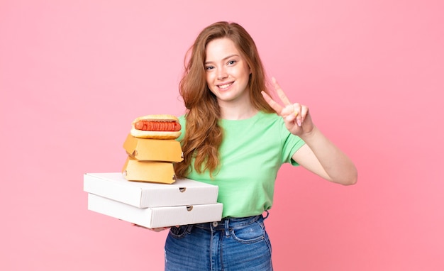 Mujer bastante pelirroja sosteniendo cajas de comida rápida para llevar