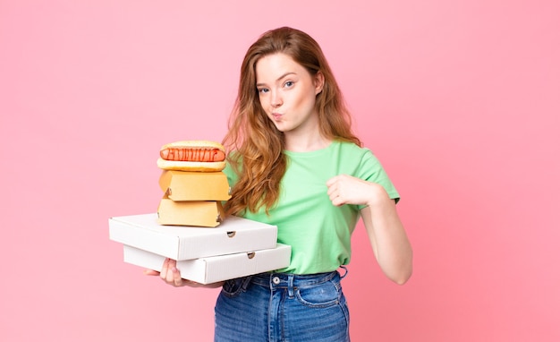 Mujer bastante pelirroja sosteniendo cajas de comida rápida para llevar