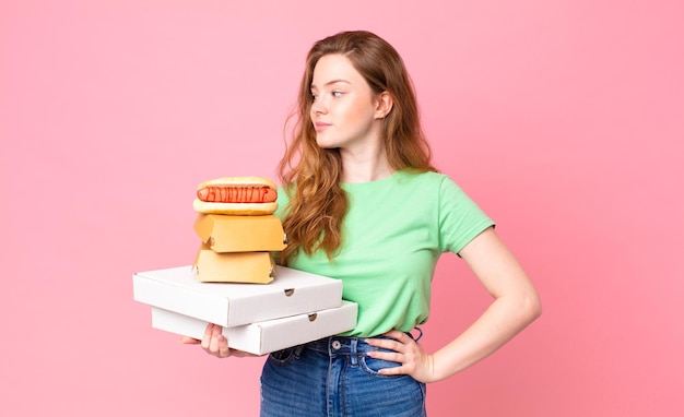 Mujer bastante pelirroja sosteniendo cajas de comida rápida para llevar