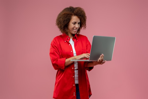 Mujer bastante rizada con chaqueta roja trabajando en una laptop