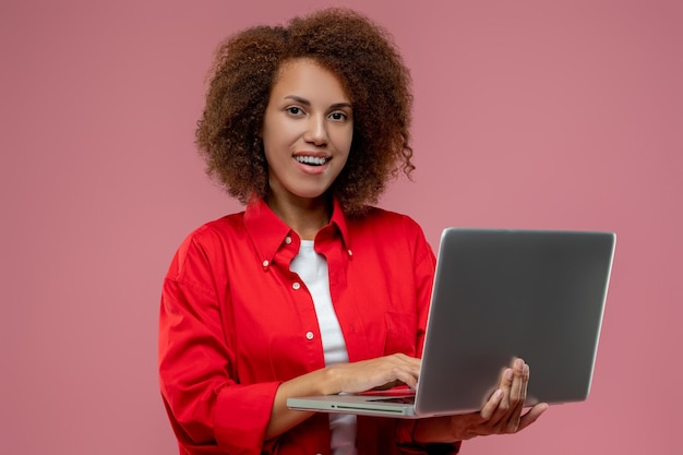 Mujer bastante rizada con chaqueta roja trabajando en una laptop