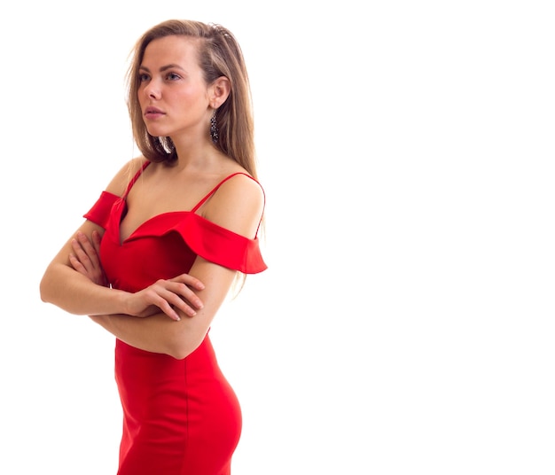 Una mujer bastante triste con el pelo largo y castaño con un vestido rojo diminuto de fondo blanco en el estudio