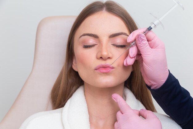 Mujer con bata de baño en clínica de belleza estética paciente procedimientos cosméticos aplicación de ácido hialurónico en los labios