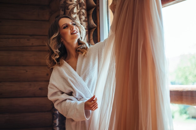 Una mujer con una bata blanca separada se cambia a un vestido. el concepto de una fecha